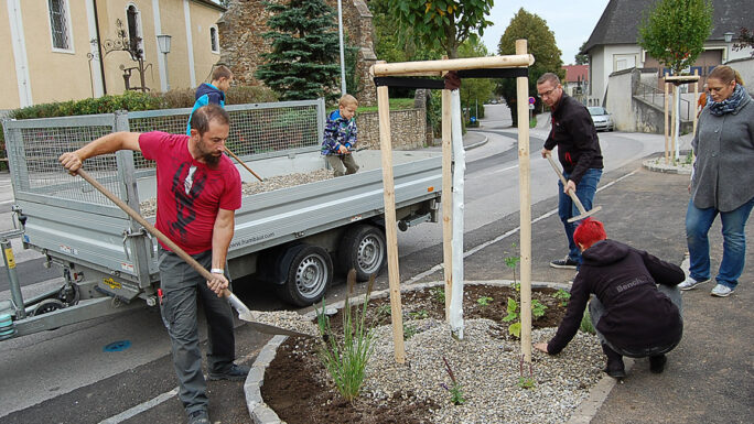 Männer und Kinder bepflanzen gemeinsam eine Blumenrabatte.