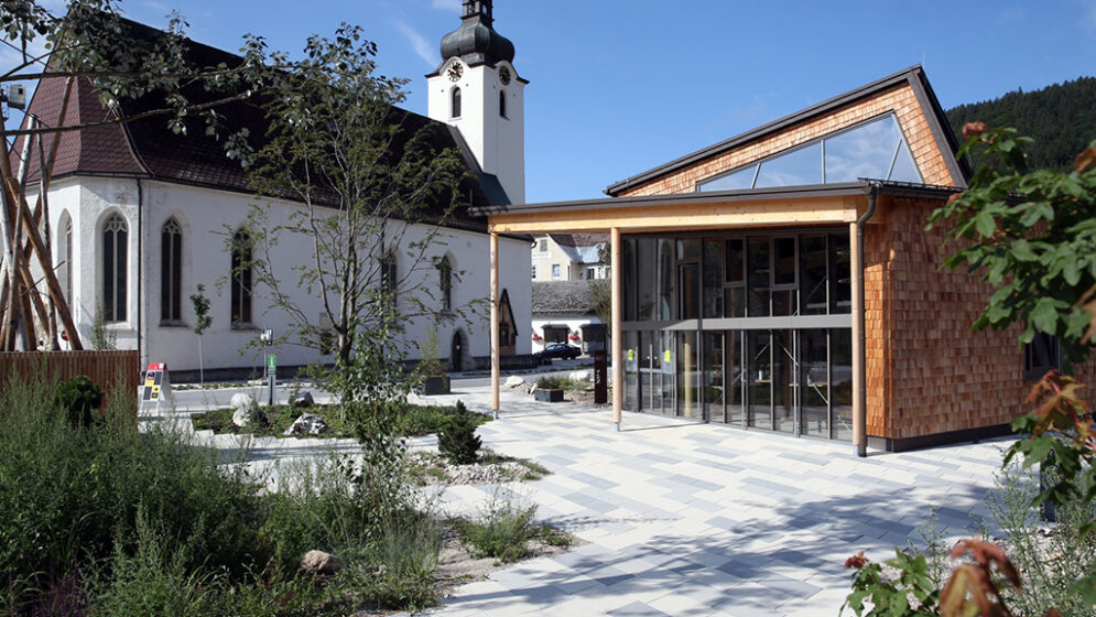Das Foto zeigt den neugestalteten Platz zwischen Pfarrkirche und Haus der Wildnissin Lunz am See.